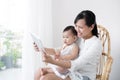 Mother and baby are looking to play and read tablet computer at Royalty Free Stock Photo