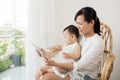 Mother and baby are looking to play and read tablet computer at Royalty Free Stock Photo