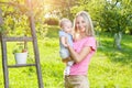 Mother with baby picking apples from an apple tree