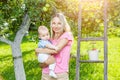 Mother with baby picking apples from an apple tree