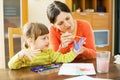 Mother and baby plays with watercolor in home