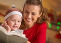 Mother and baby reading book in christmas decorated kitchen Royalty Free Stock Photo