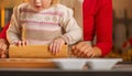 Mother and baby rolling pin dough in christmas decorated kitchen Royalty Free Stock Photo