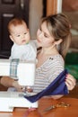 Mother with a baby shows her work, sewing at home. Raising children, child care, nanny. Royalty Free Stock Photo