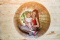 Mother and baby sitting in wooden tunnel. Eco-friendly playground. Soft light Royalty Free Stock Photo