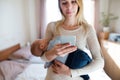 Mother with baby son in her arms and smartphone, texting Royalty Free Stock Photo