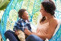 Mother With Baby Son Relaxing On Outdoor Garden Swing Seat