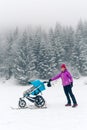 Mother with baby stroller enjoying motherhood in winter forest Royalty Free Stock Photo