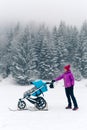 Mother with baby stroller enjoying motherhood in winter forest Royalty Free Stock Photo