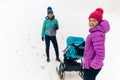 Mother with baby stroller enjoying winter forest with female friend or partner, family time. Hiking or power walking woman with Royalty Free Stock Photo