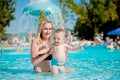 Mother and baby in swimming pool. Parent and child swim in a tropical resort. Summer outdoor activity for family with kids. Royalty Free Stock Photo