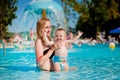 Mother and baby in swimming pool. Parent and child swim in a tropical resort. Summer outdoor activity for family with kids. Royalty Free Stock Photo