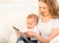 Mother and baby with tablet computer on the couch at home Royalty Free Stock Photo