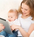 Mother and baby with tablet computer on the couch at home Royalty Free Stock Photo