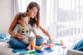 Mother and baby toddler playing building with learning toy stacking blocks at home. Early age education. Kids hand brain and fine Royalty Free Stock Photo
