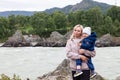 Mother and baby walking on nature outdoors. Family in rocky nature background with river. Loving woman with child in countryside.