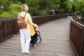 Mother pushing a stroller on wooden bridge