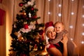 Mother with beautiful baby near Christmas tree