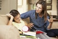 Mother Becoming Frustrated With Daughter Whilst Doing Homework Sitting On Sofa At Home