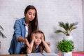 Mother becoming frustrated with daughter whilst doing homework sitting at the table at home in learning difficulties Royalty Free Stock Photo