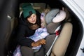 Mother belt child safety seat chair with baby girl is on back seat of car Royalty Free Stock Photo