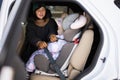 Mother belt child safety seat chair with baby girl is on back seat of car Royalty Free Stock Photo