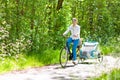 Mother on bicycle with baby bike trailer in park