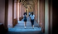 Mother in black hat and daughter in shorts walking down promanade in sneakers and shorts and pants