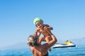 Mother in black sunglasses and smiling baby boy son in green baseball cap playing in the sea in the day time. Positive human emoti Royalty Free Stock Photo