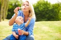 Mother Blowing Bubbles For Young Boy In Garden Royalty Free Stock Photo