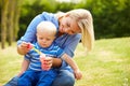 Mother Blowing Bubbles For Young Boy In Garden Royalty Free Stock Photo