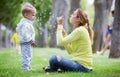 Mother blowing soap bubbles outdoors, little son watching her