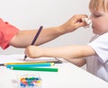 A mother blows her nose to a 3-year-old girl who draws with pencils. Cocnept runny nose and allergies in children, paediatrist