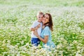 A mother in a blue dress is having fun with her blond son in a blooming field of daisies. Enjoy the aroma of a bouquet of daisies Royalty Free Stock Photo