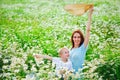 A mother in a blue dress is having fun with her blonde son in a blooming field of daisies. Together in nature Royalty Free Stock Photo