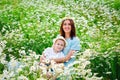 A mother in a blue dress is having fun with her blonde son in a blooming field of daisies. Together in nature Royalty Free Stock Photo