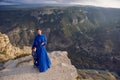 mother in a blue dress with her son stands on the cliff of the Sulak canyon