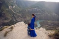 mother in a blue dress with her son stands on the cliff of the Sulak canyon