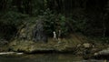 Mother and boy walking along the river and giant stones. Creative. Green dense forest on the background.