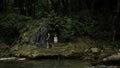 Mother and boy walking along the river and giant stones. Creative. Green dense forest on the background.