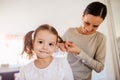 Mother braiding hair of her daughter in the morning