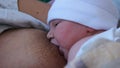 Mother Holding Newborn in Embrace and Breastfeed Her Infant, Close-up View of Baby Head, Tenderness and Care of Motherhood.