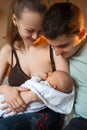 Mother breast feeding and hugging her baby. Father watches the process. Happy family life. Man was born Royalty Free Stock Photo