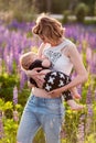 Mother breastfeeding her baby in a field of purple flowers.