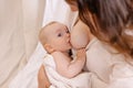 Mother is breastfeeding her baby. Woman in white and child on her arms. Kid sucks breast milk. Royalty Free Stock Photo