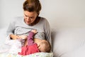 Mother breastfeeding her newborn baby while pumping milk from her other breast to store it in a special breastfeeding bag