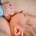 A mother is breastfeeding a newborn baby with a maternity hospital bracelet on her arm. A newly born child in the clinic in the Royalty Free Stock Photo