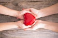 Mother care or love concept with child and mom hands holding a red heart shape Royalty Free Stock Photo