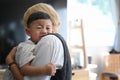 Mother caressing and calming down her crying baby son while standing at home. Royalty Free Stock Photo