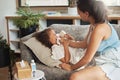 A mother caring for her sick child with flu at home by blowing her nose. Ill little girl and daughter suffering from Royalty Free Stock Photo